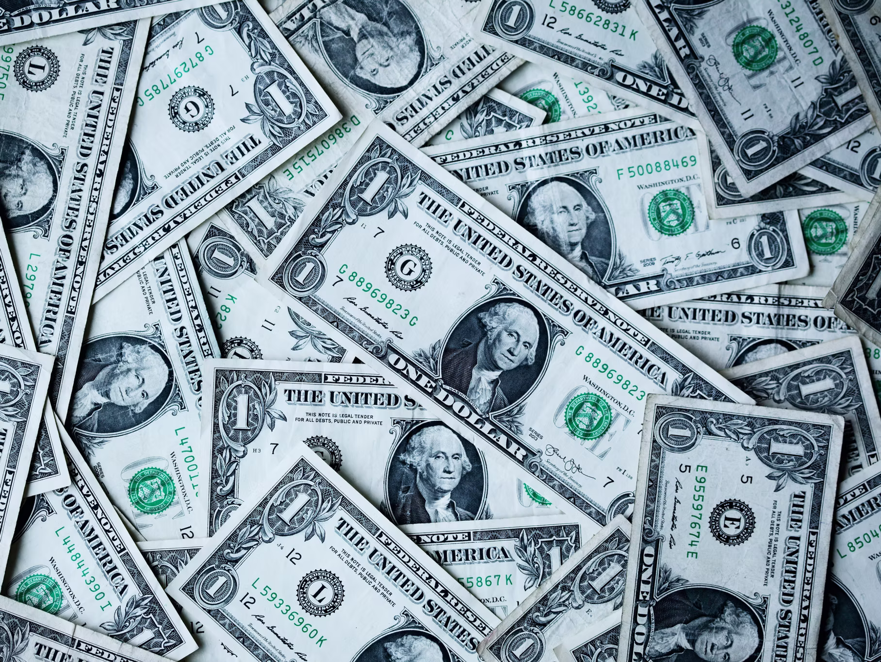 Scattered U.S. dollar bills representing financial issues related to payroll tax problems and IRS penalties.