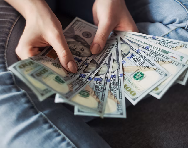 Hands holding fanned-out hundred-dollar bills, symbolizing financial relief and tax resolution services offered by Liberty Financial Solutions.
