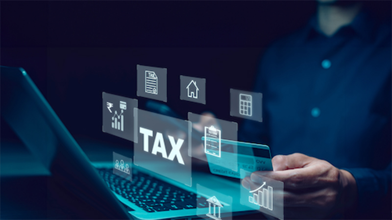 Person using laptop with tax-related icons and documents, emphasizing tax preparation and financial services.